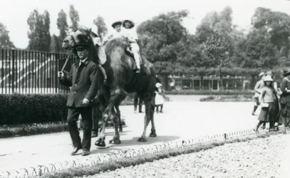 Two young visitors riding a Bactrian camel, led by a keeper, at London Zoo, August 1922